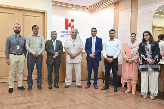 Both teams together after the signing, beneath the Indus Hospital & Health Network sign