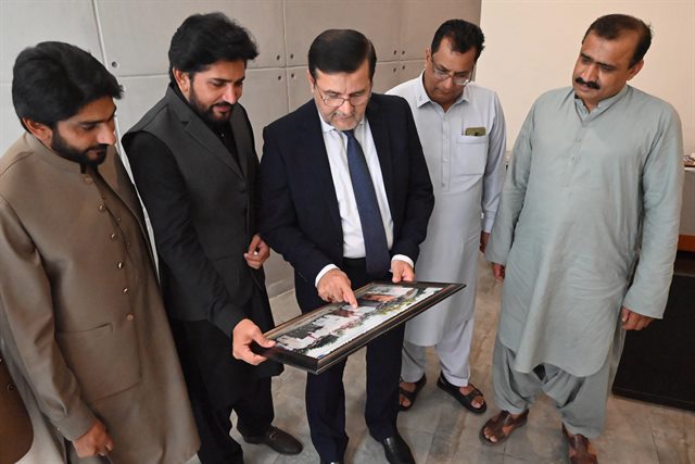 Colleagues showing the Director a framed photograph