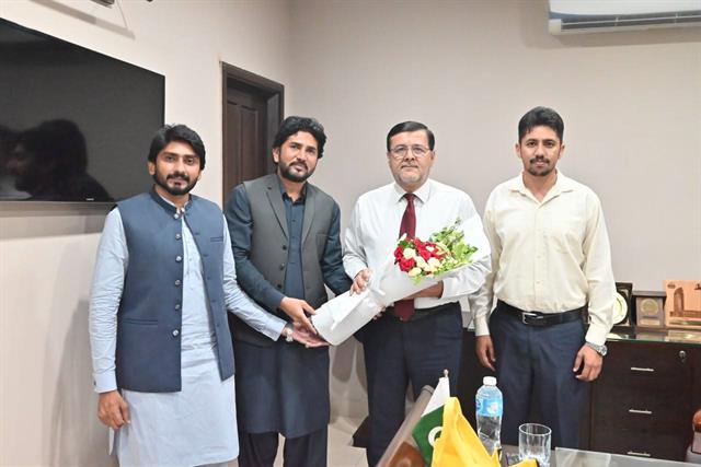 Faculty members welcoming the Director with a bouquet in a department office