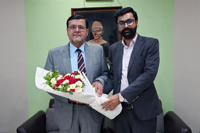 A faculty member welcomes the Director with a bouquet