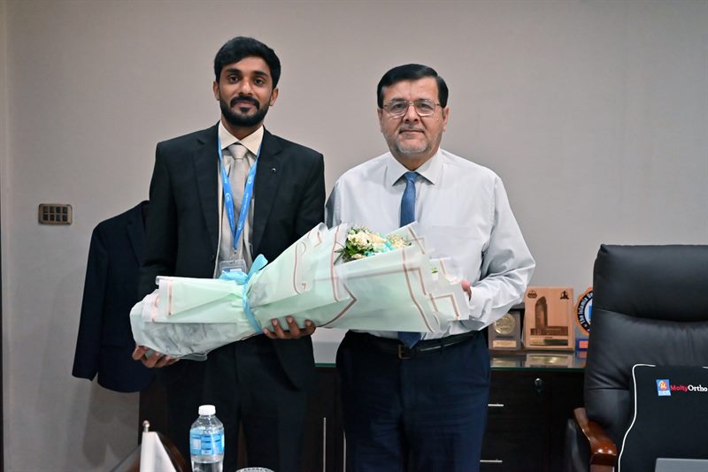 The Director receiving a bouquet from a visitor in his office