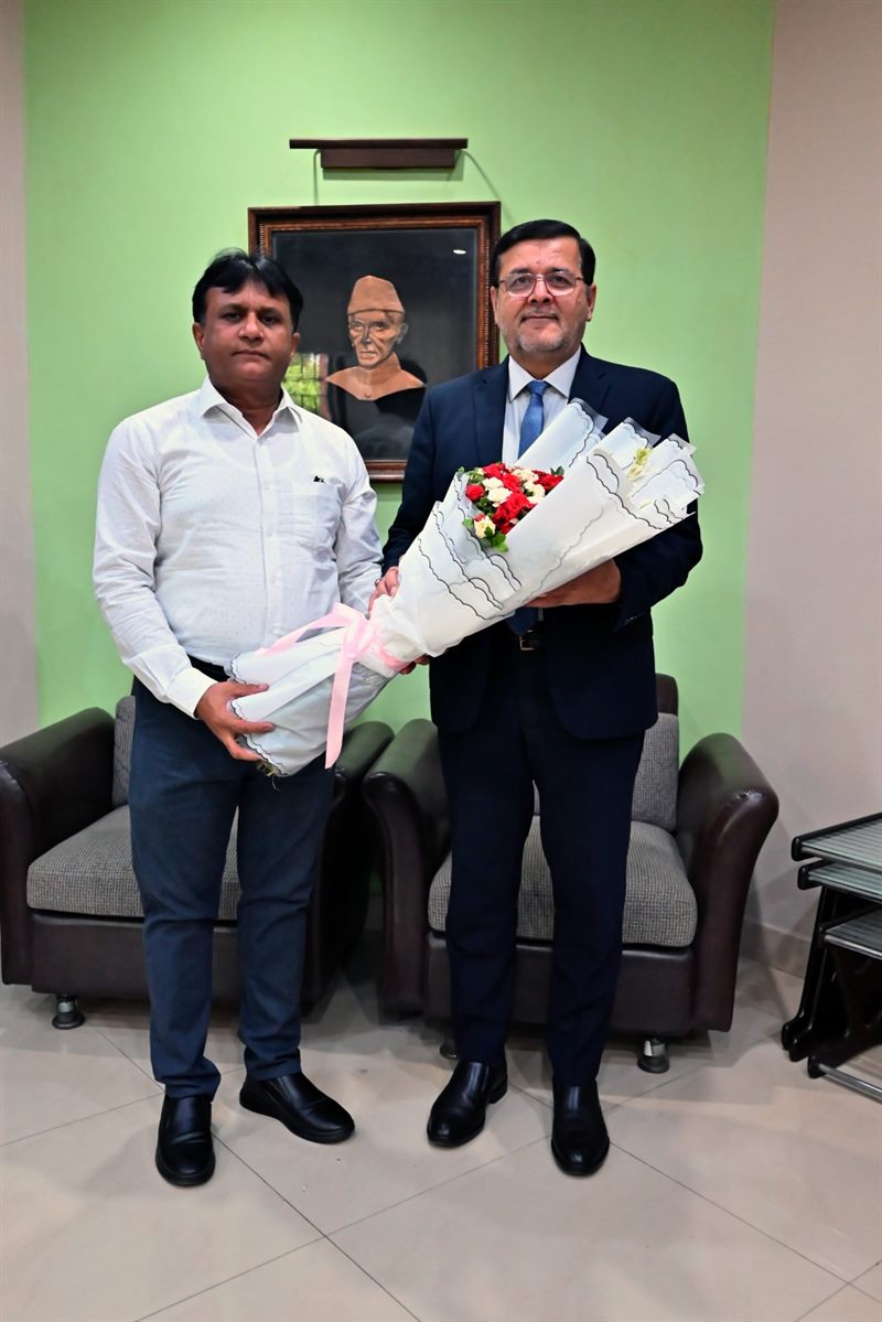 The Director with a guest, both holding bouquets, at the Directorate