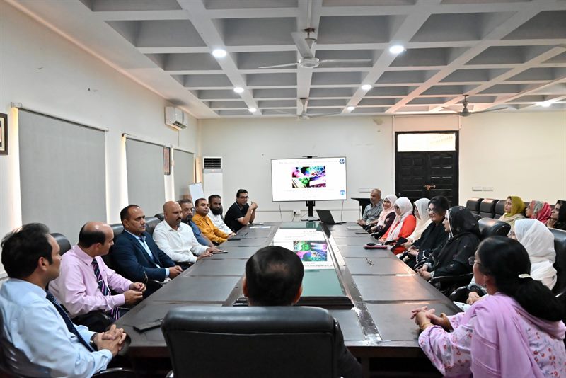 Faculty members around the conference table with a research presentation on screen