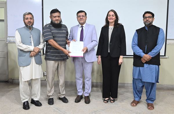 A promoted colleague holding his letter, flanked by senior officials of the Campus